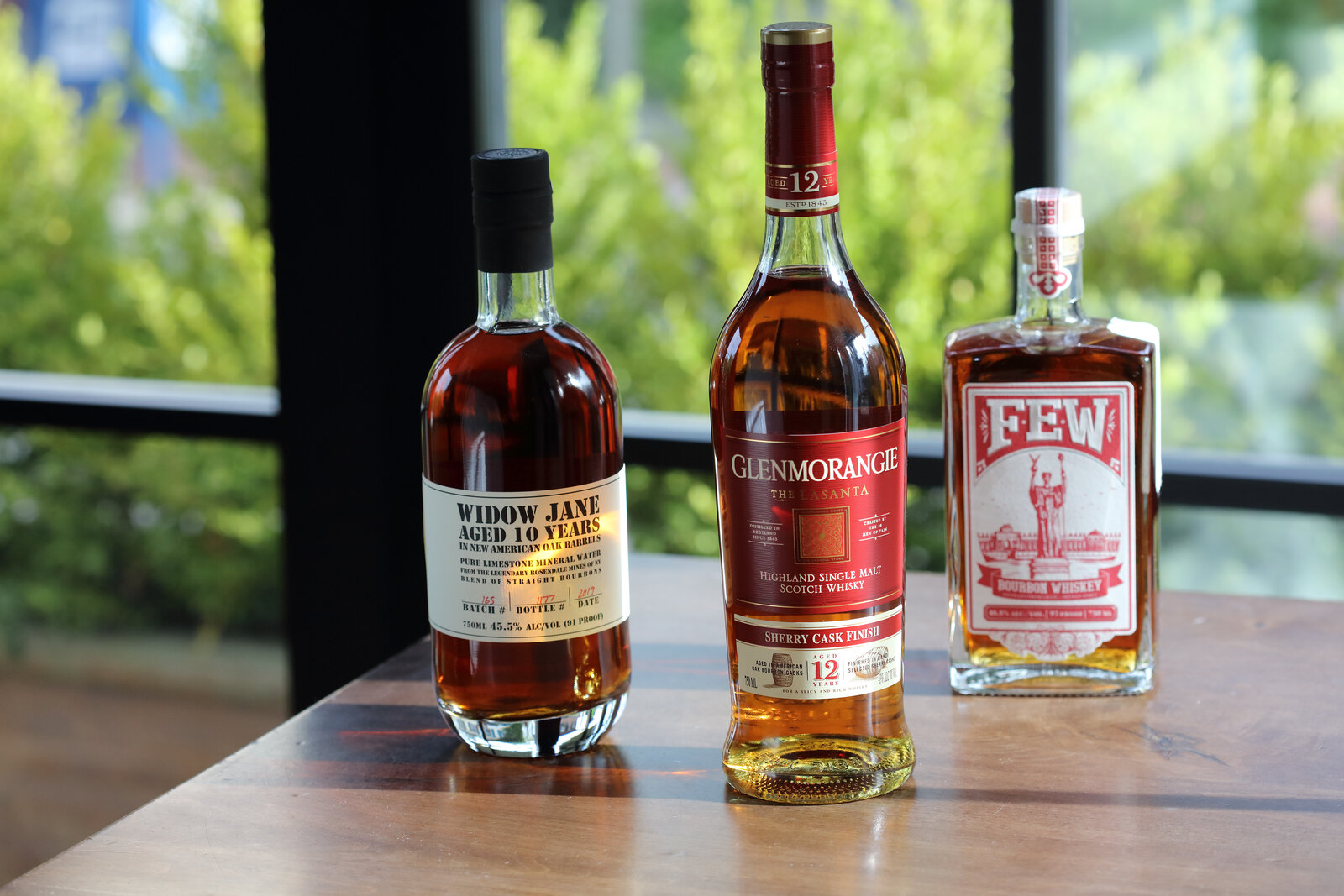 Three whiskey bottles — Widow Jane, Glenmorangie, FEW